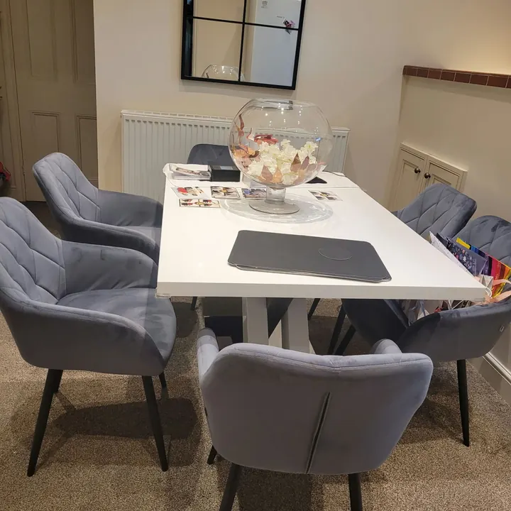 Tidy dining area with a white table and grey chairs after a clean