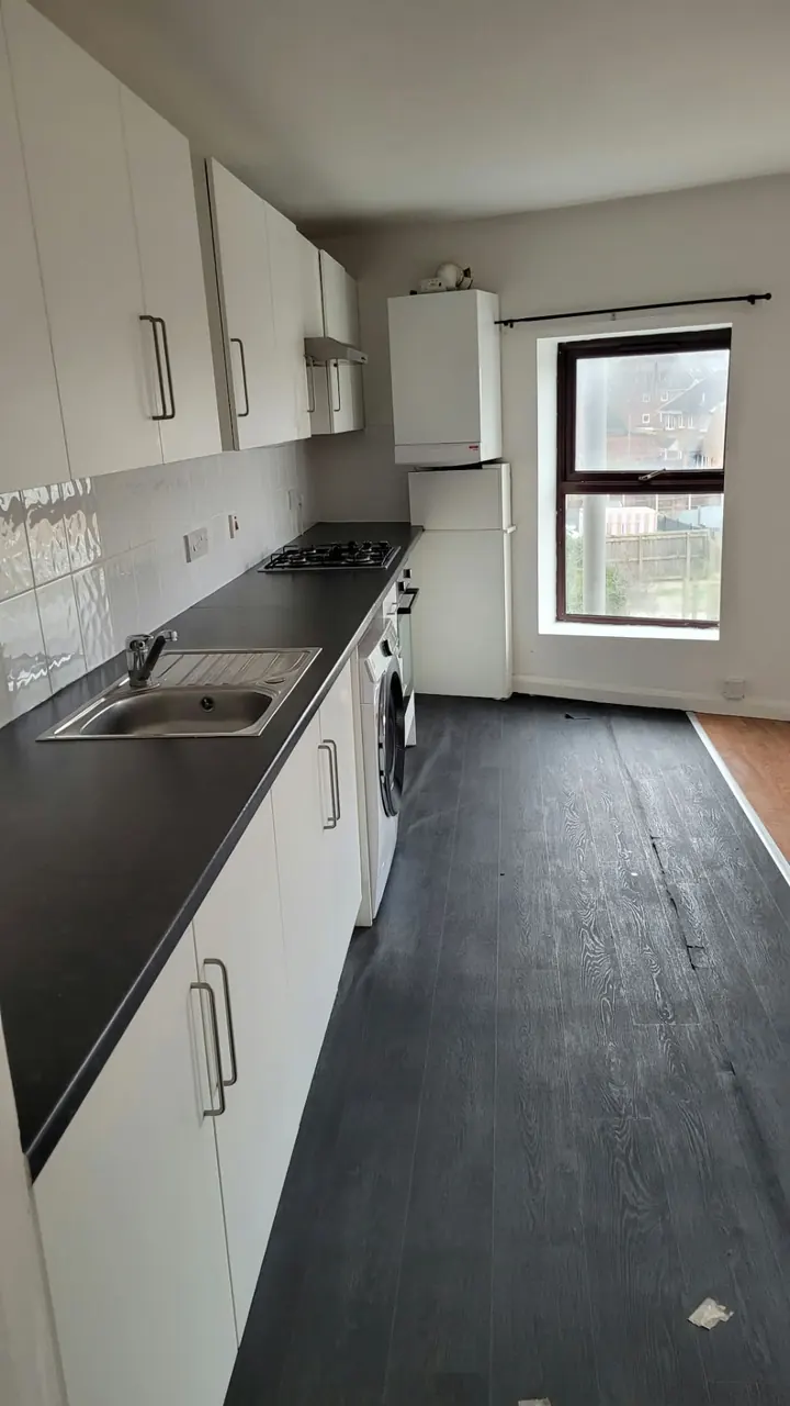 Empty kitchen with wiped white cupboards and worktop after a clean